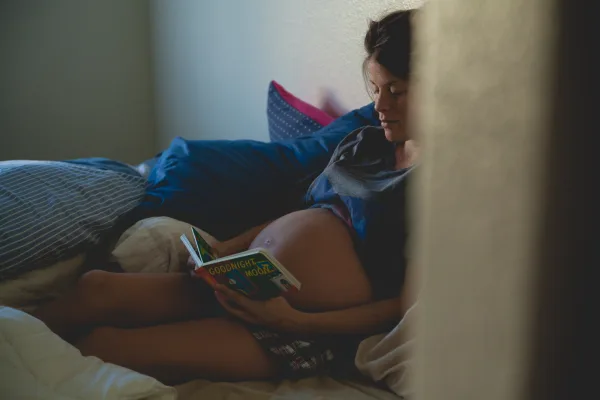 Pregnant woman reading a book in bed