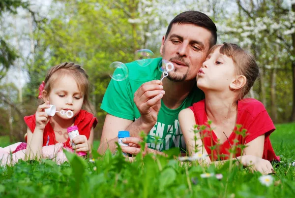 Dad and daughters blowing bubbles outside