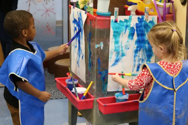Two children painting on easels