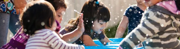 Children gather around a water table playing