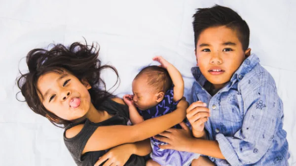 Children from baby to elementary age cuddling on bed