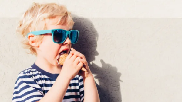 A child with sunglasses on eating ice cream