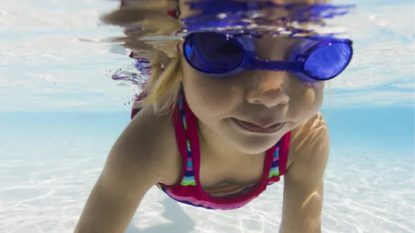 Child swimming underwater with goggles on