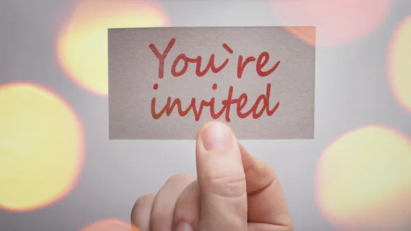 A hand holding up an invitation card